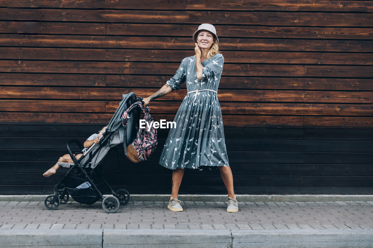 Woman with baby stroller standing on footpath