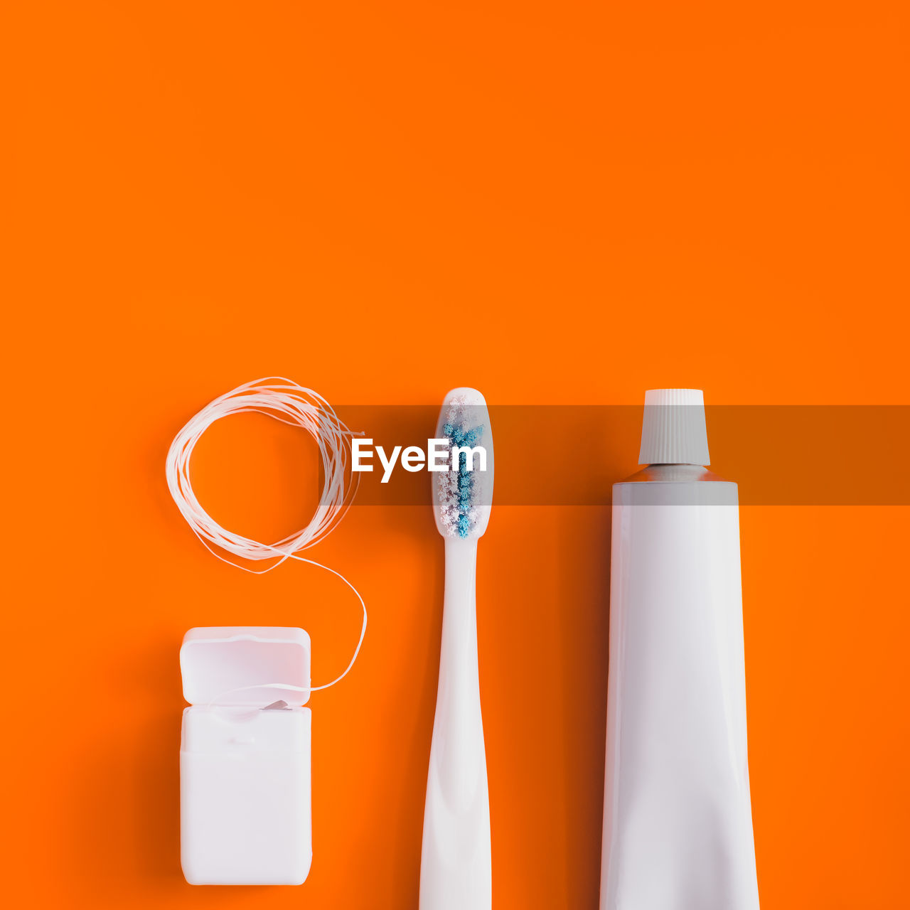 Close-up of toothbrush with toothpaste over orange background