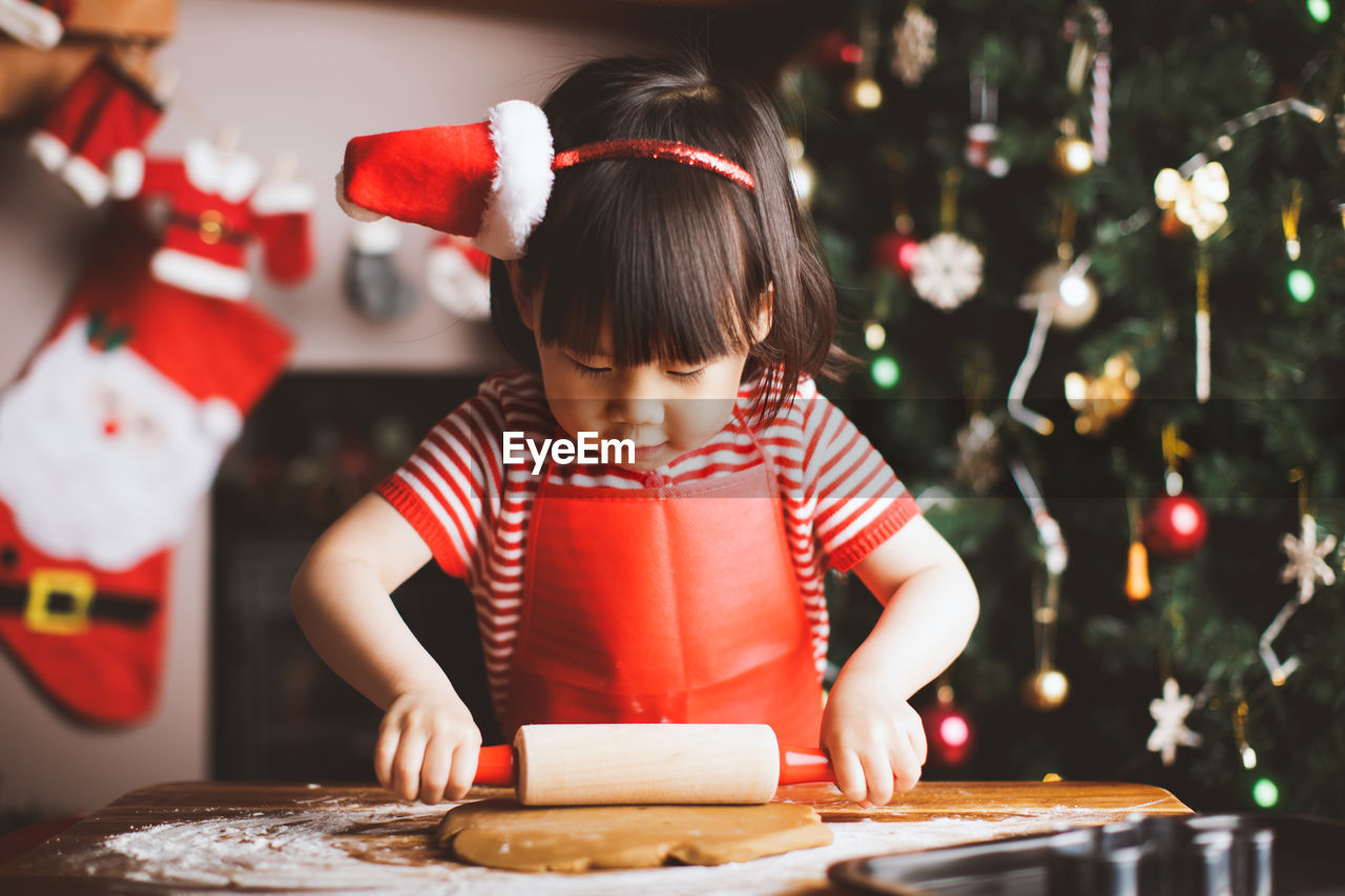 Girl making cookies at table during christmas