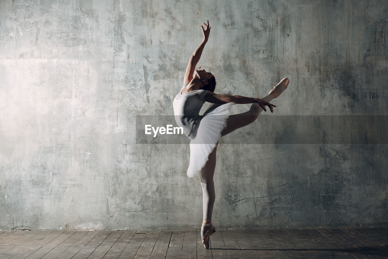 Woman dancing against gray wall