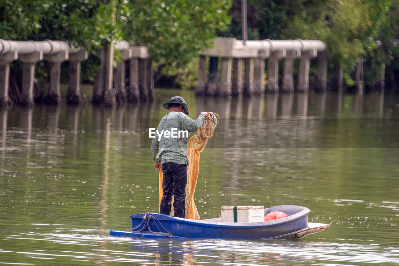 REAR VIEW OF MAN IN BOAT