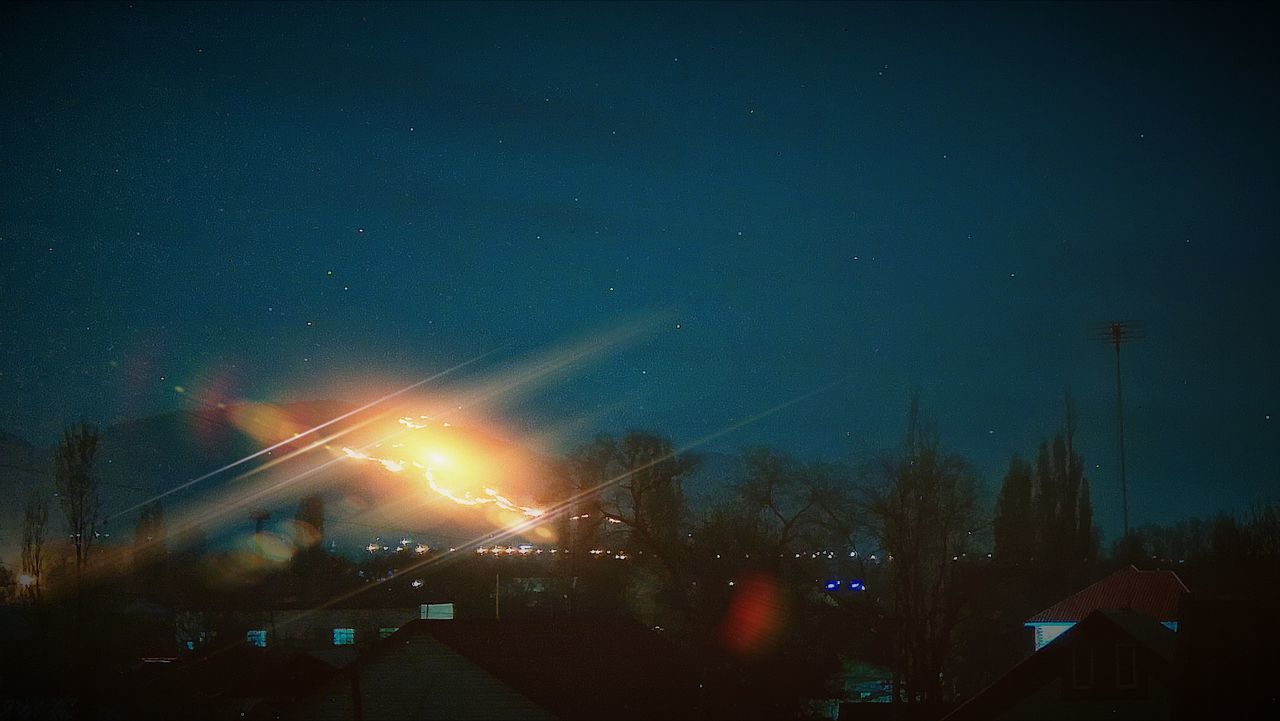 LOW ANGLE VIEW OF ILLUMINATED CITY AGAINST SKY