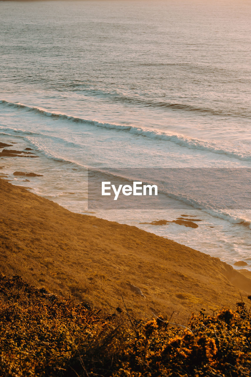 Aerial shot of a massive beach with waves during a super sunny sunset on vintage tones