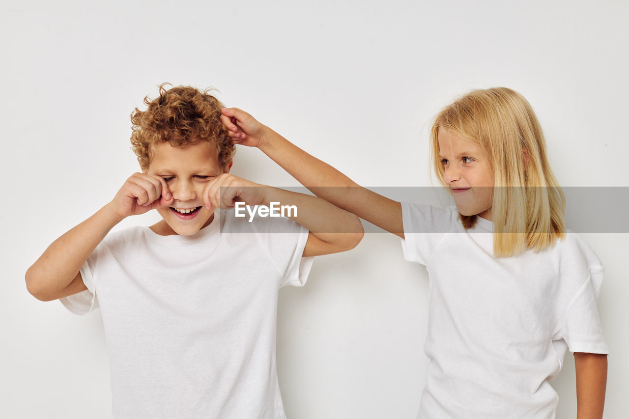 Cute sibling fighting against white background