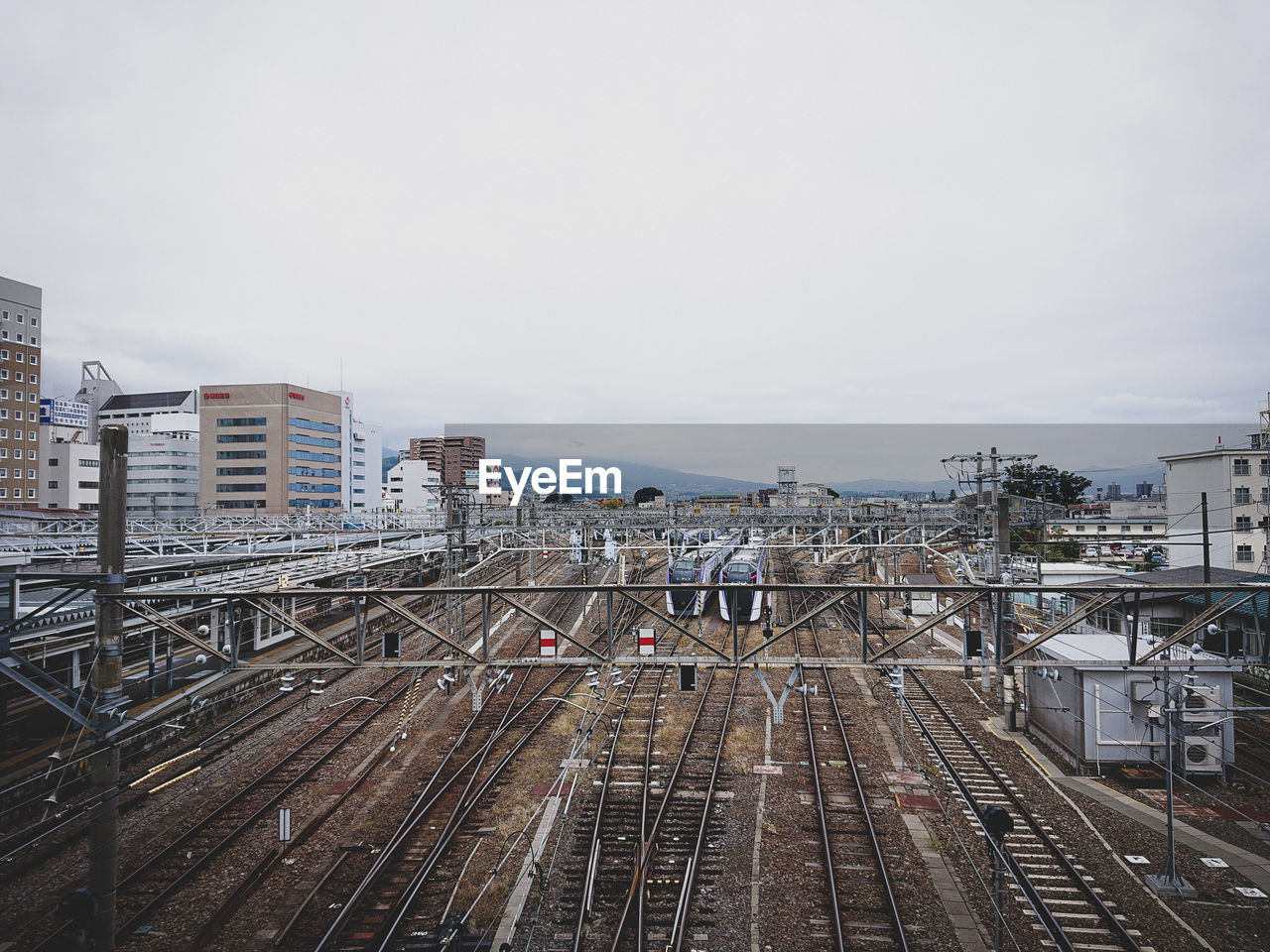 HIGH ANGLE VIEW OF RAILROAD TRACKS BY BUILDINGS IN CITY AGAINST SKY