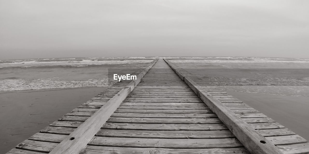 Boardwalk leading towards beach against sky