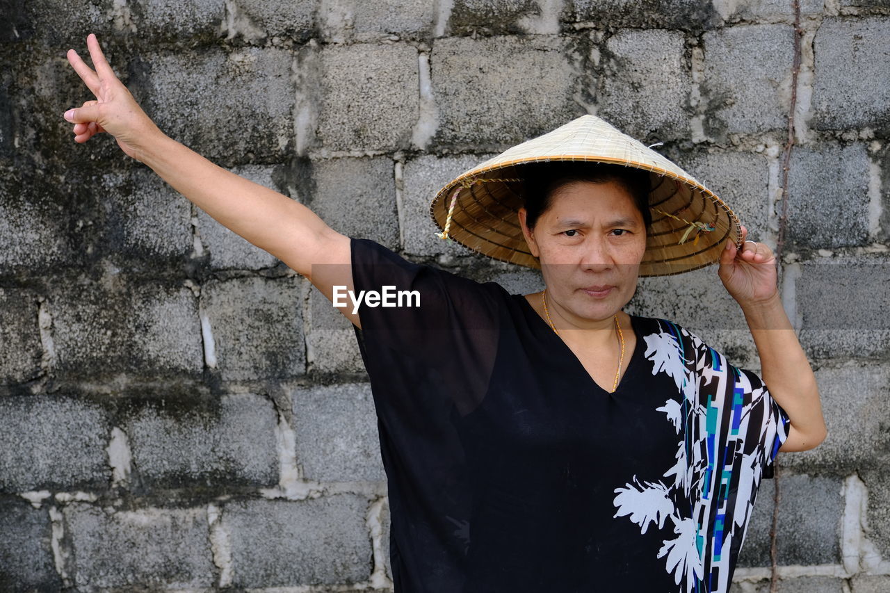 Mature woman wearing casuals while standing against wall