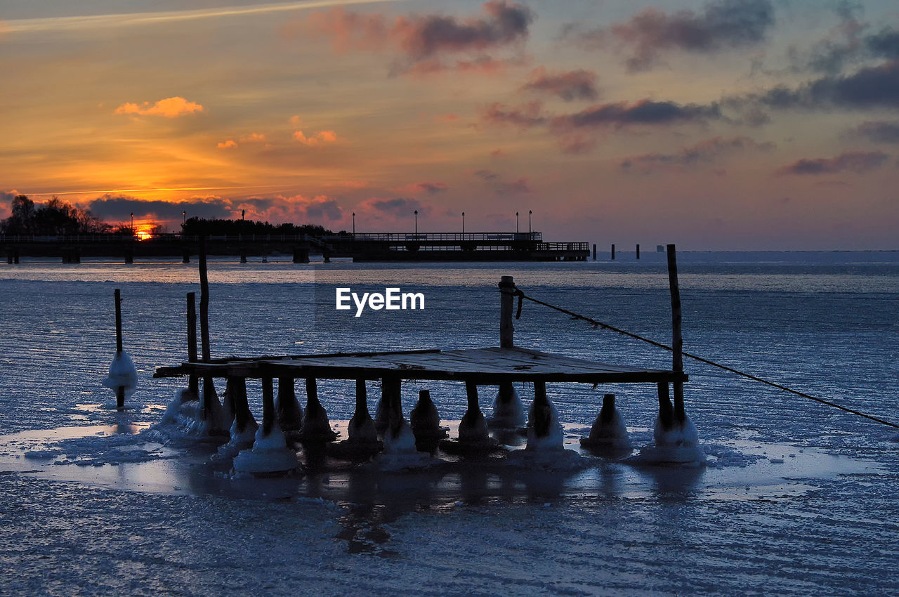 Pier over sea against sky during sunset