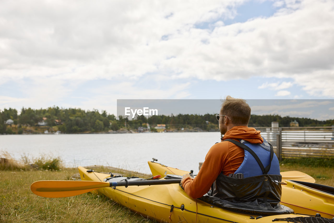 Rear view of man sitting in kayak and looking at sea