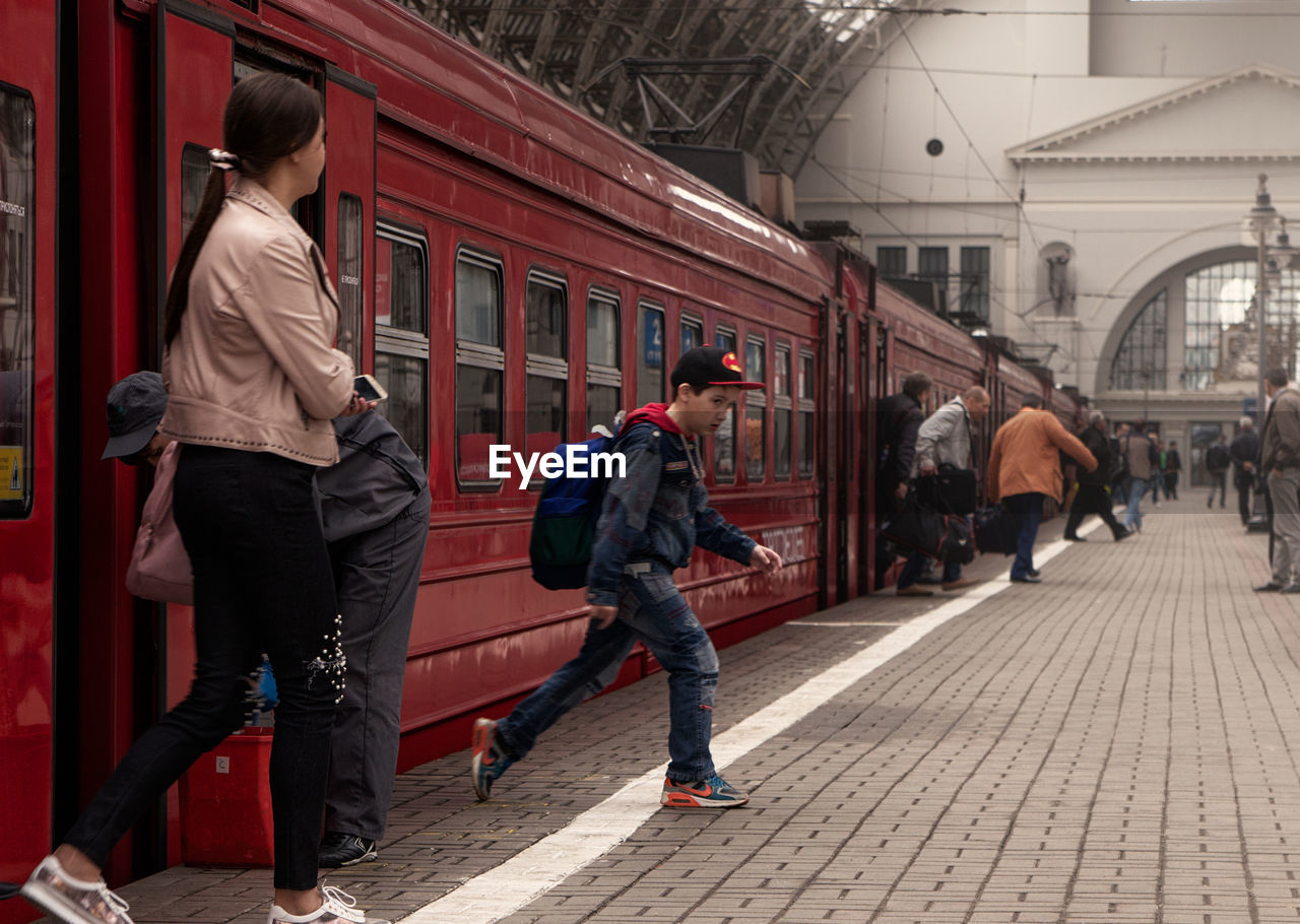 REAR VIEW OF PEOPLE WALKING ON FOOTPATH