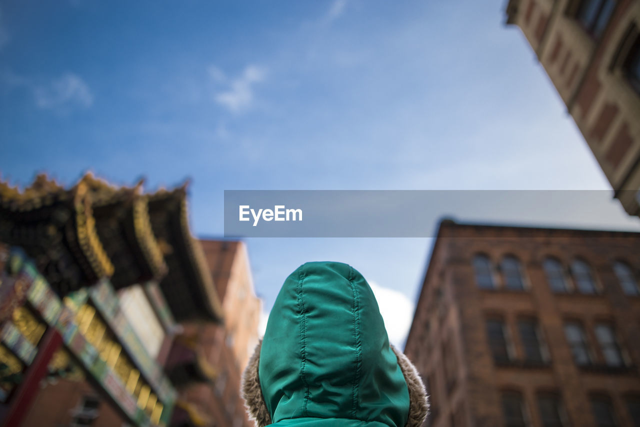 Low angle view of person wearing hooded shirt against buildings