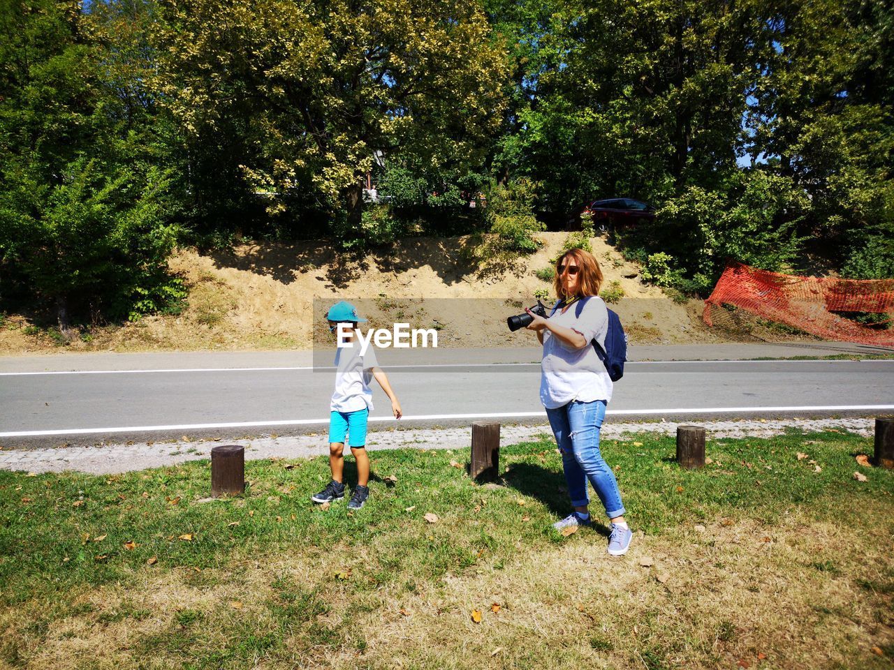 Mother photographing by son while standing on grassy field