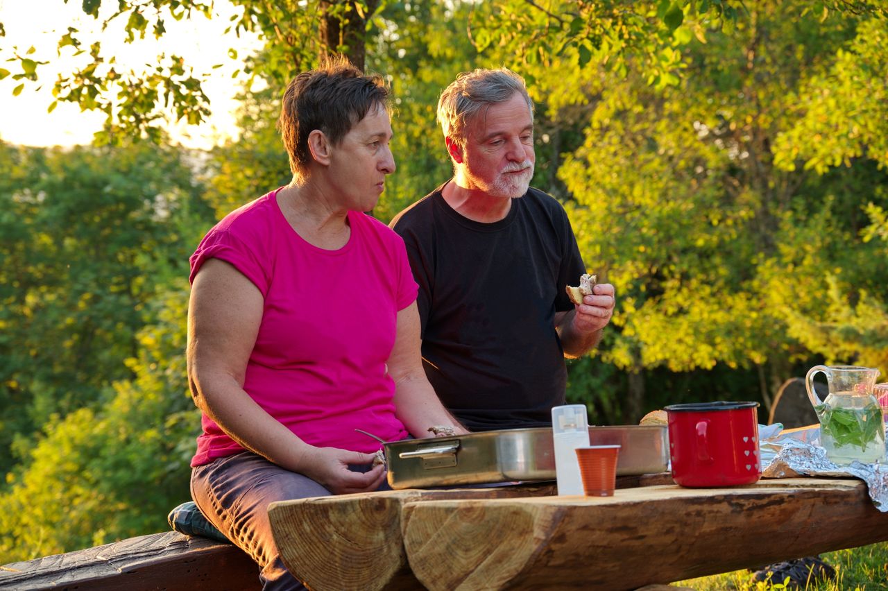 Senior couple sitting at the table in nature and eating