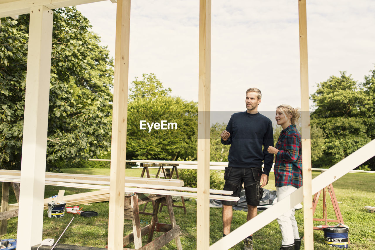 Couple discussing while looking at incomplete shed in farm