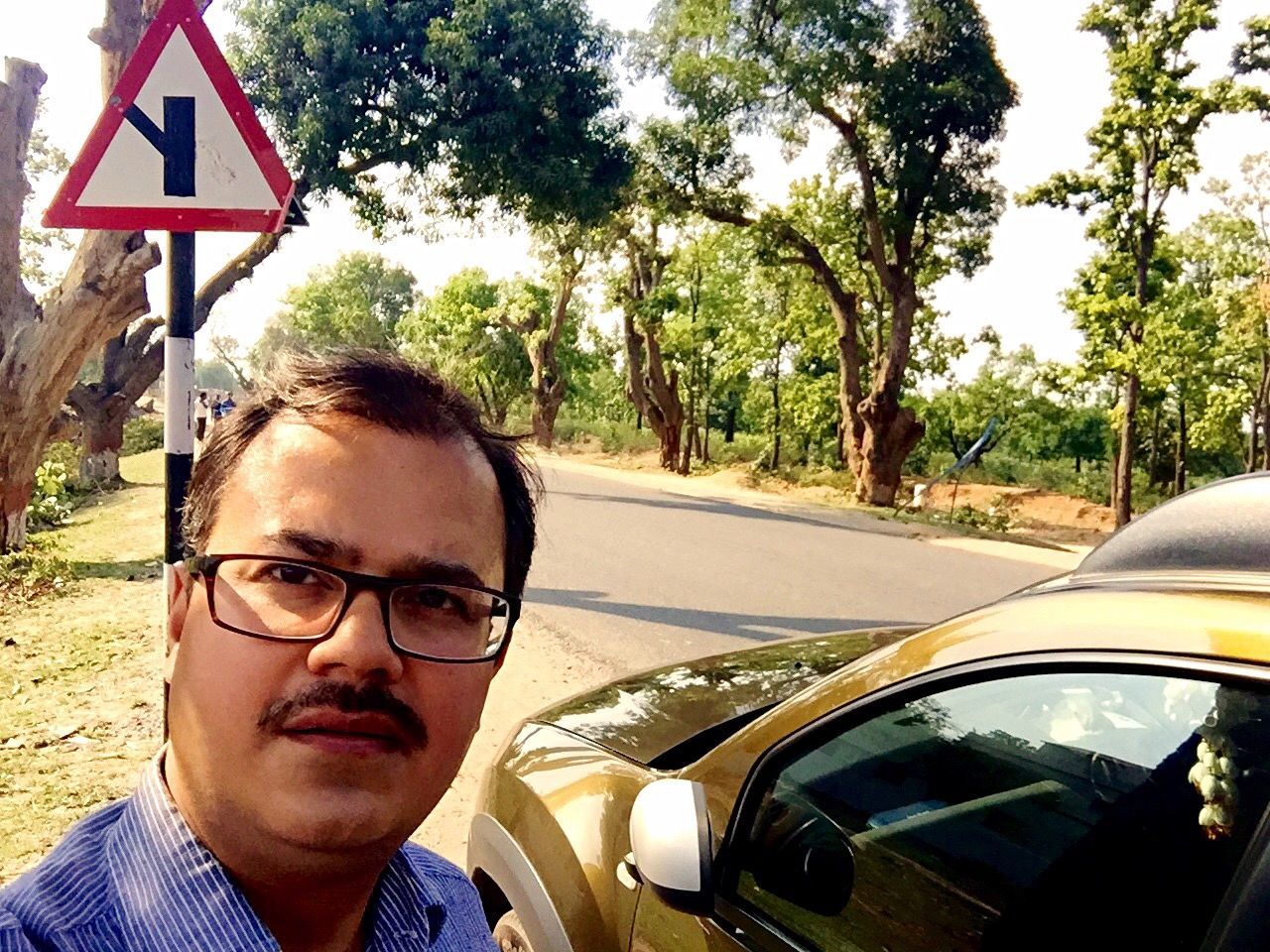 Man by car on street against trees