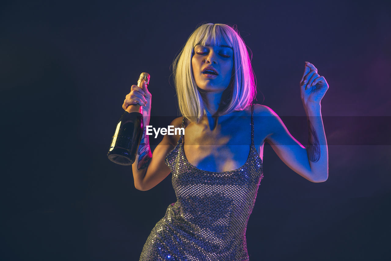 Woman holding bottle against black background