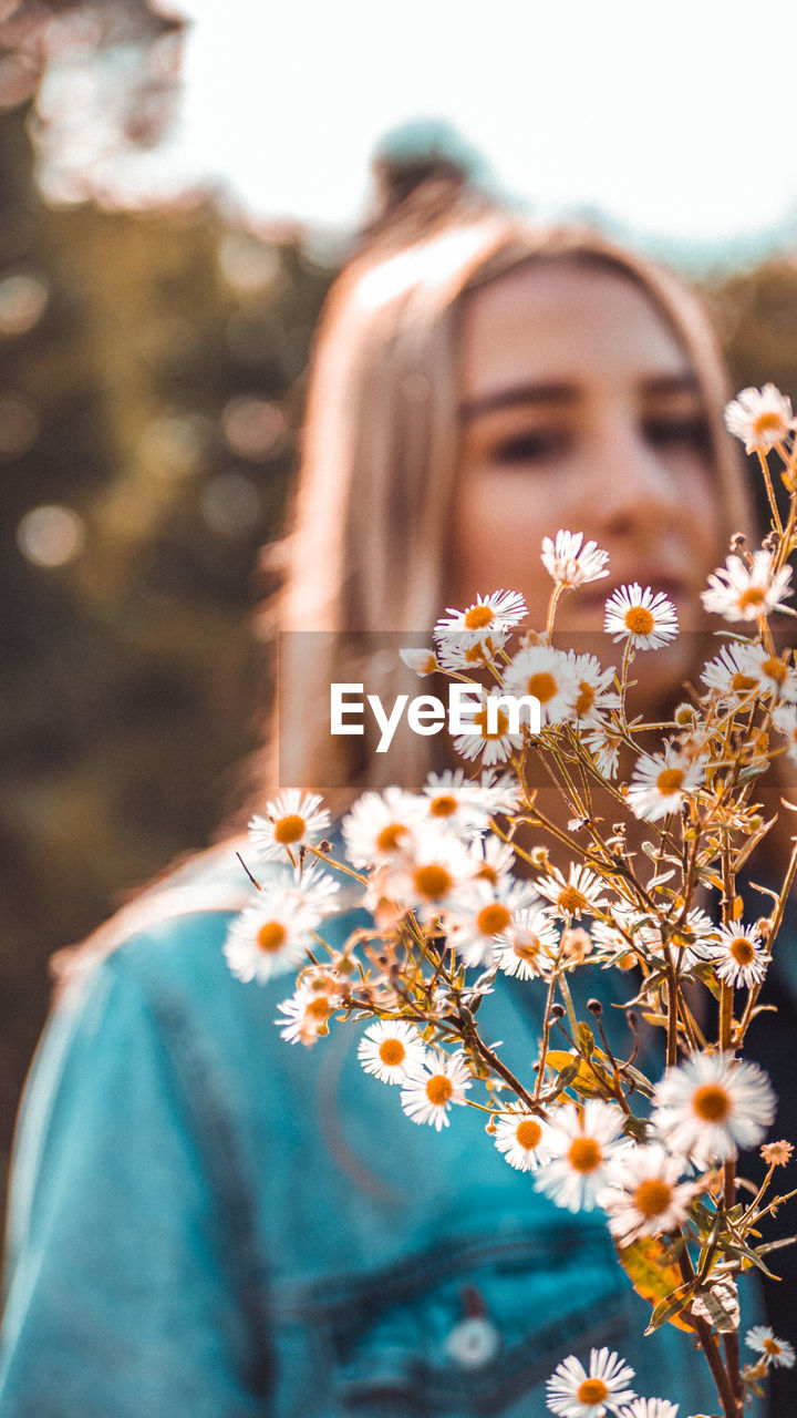 Portrait of teenage girl standing by flowers