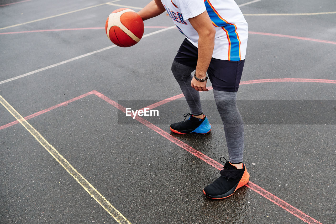 Cropped image of unrecognizable male playing basketball at the court. sport concept.