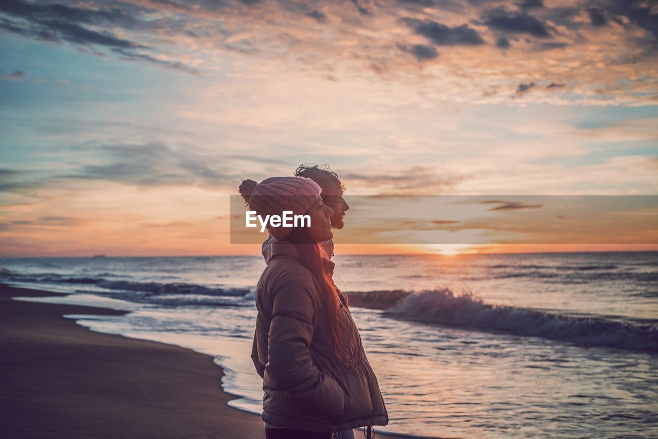 SIDE VIEW OF MAN LOOKING AT SEA AGAINST SKY