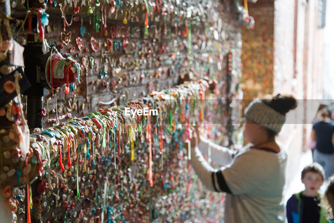 Side view of woman standing by gum wall