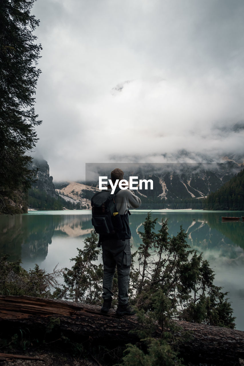 Man standing by lake against sky