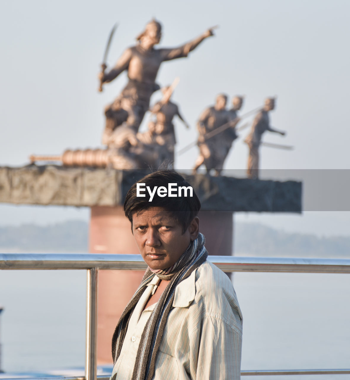 Portrait of young man standing against railing