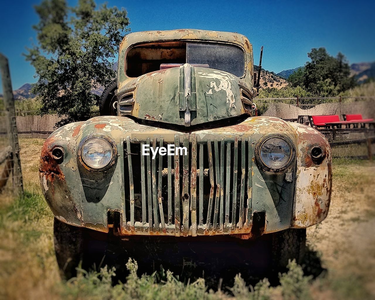 Old rusty car on field against sky