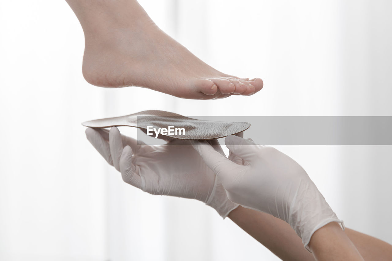 Cropped hand of doctor holding insoles by patient feet