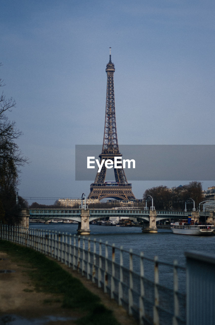 Low angle view of eiffel tower over river against sky at dusk