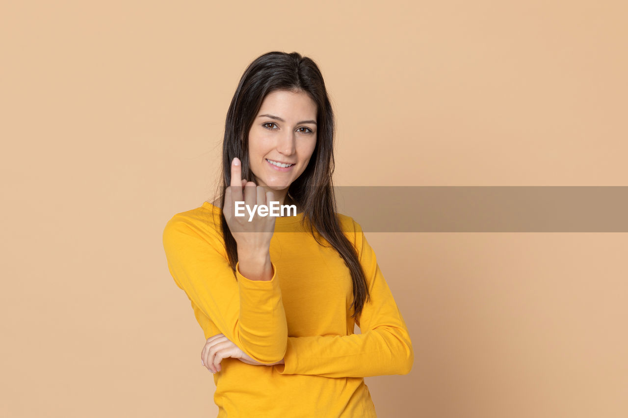 PORTRAIT OF A SMILING WOMAN AGAINST YELLOW BACKGROUND