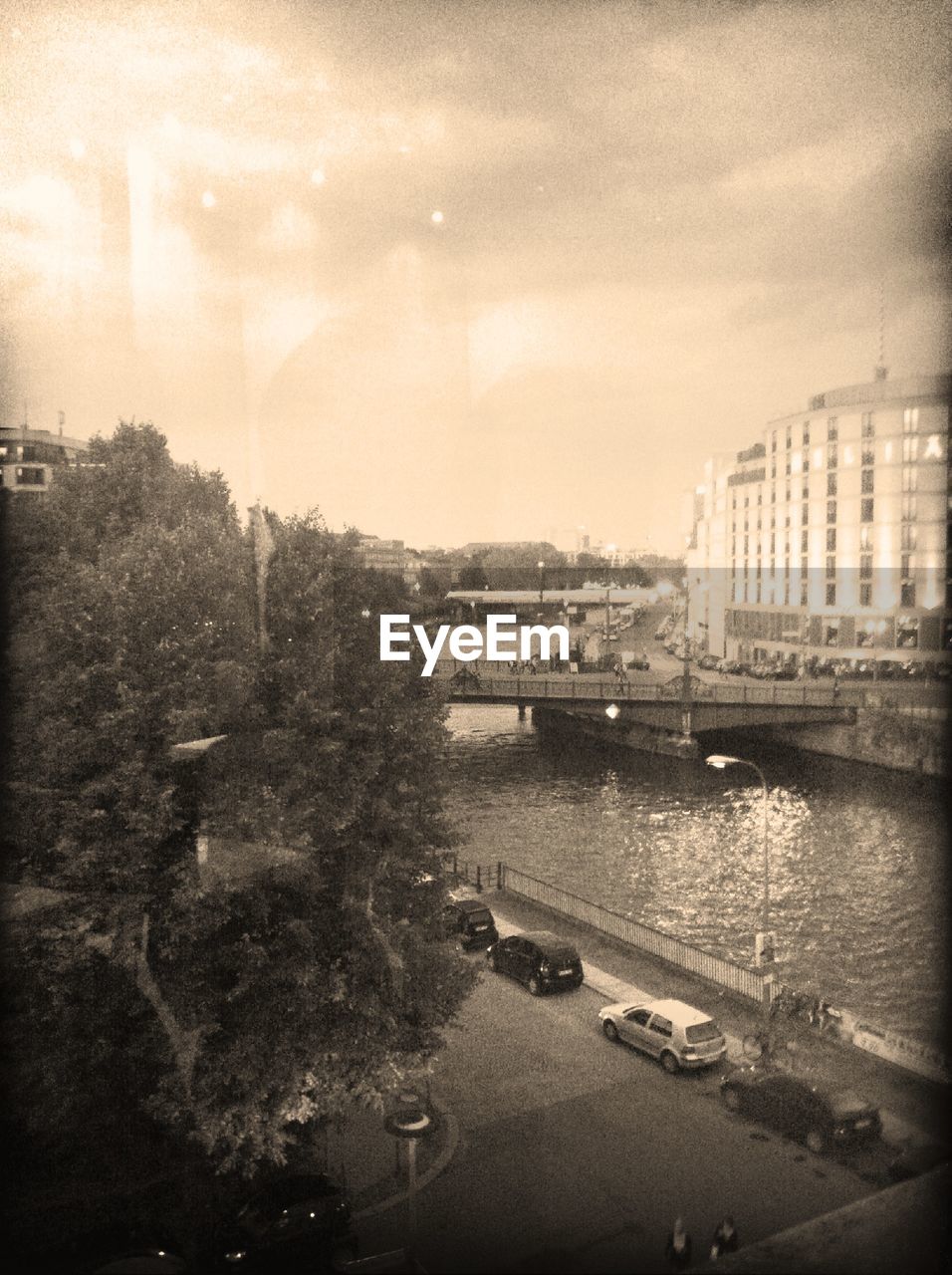 High angle view of street by river and building against cloudy sky