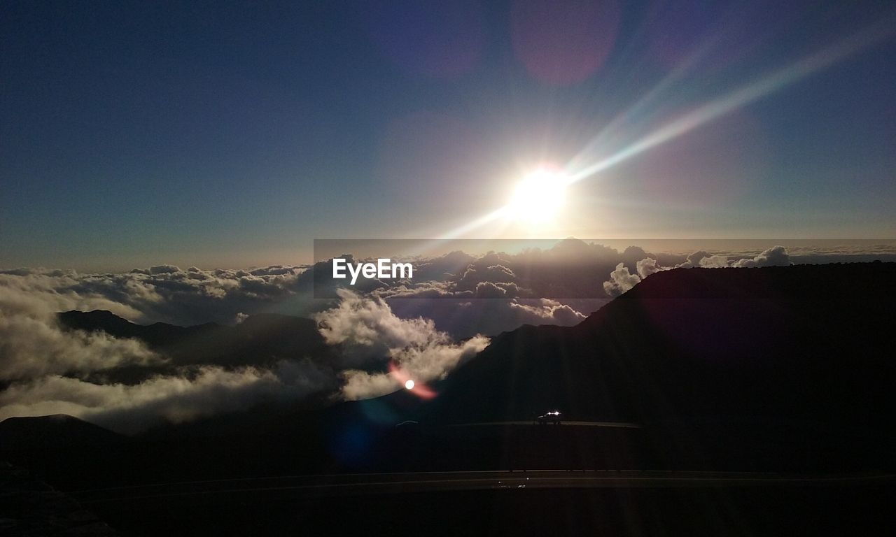 SUN SHINING THROUGH CLOUDS OVER MOUNTAINS