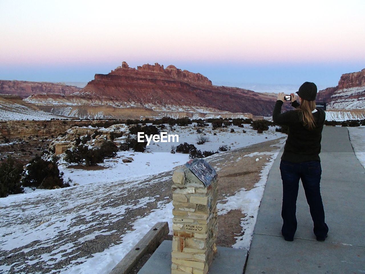 WOMAN PHOTOGRAPHING WITH SNOW COVERED LANDSCAPE