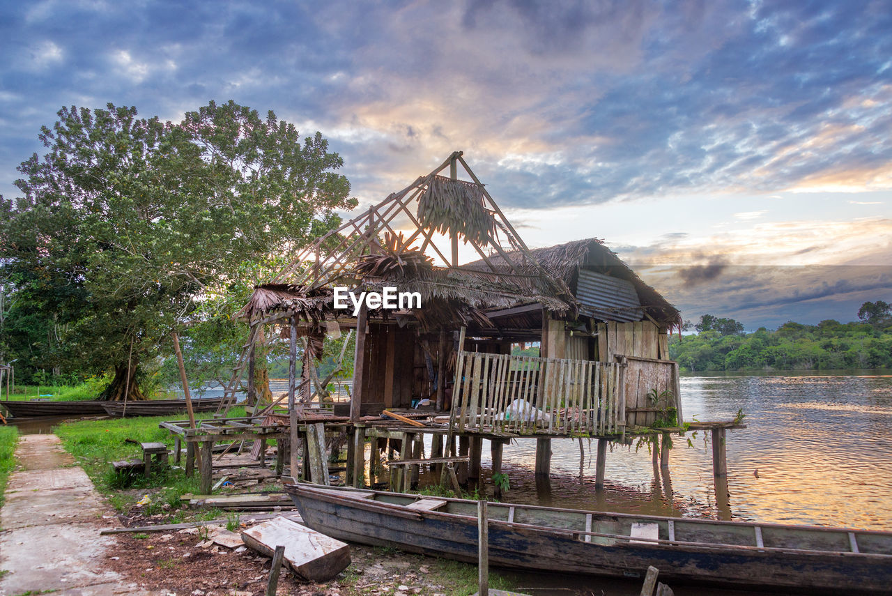 Weathered shack at bank of javary river against cloudy sky during sunset