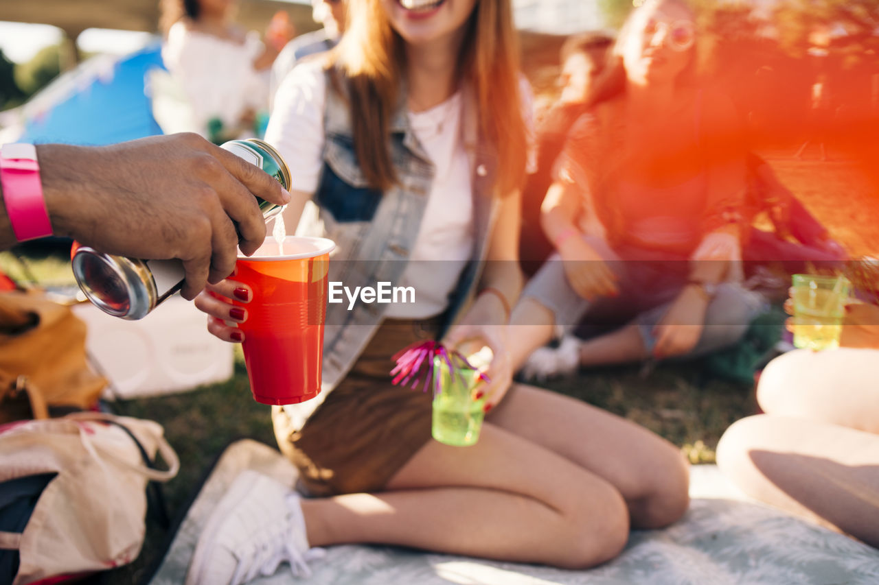 Cropped image of man pouring alcohol in friend's glass at party in festival