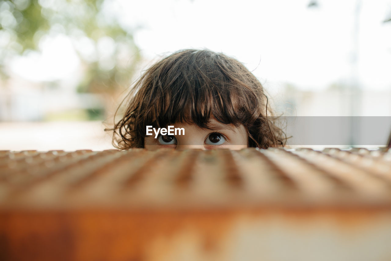 Portrait of boy hiding behind curtain