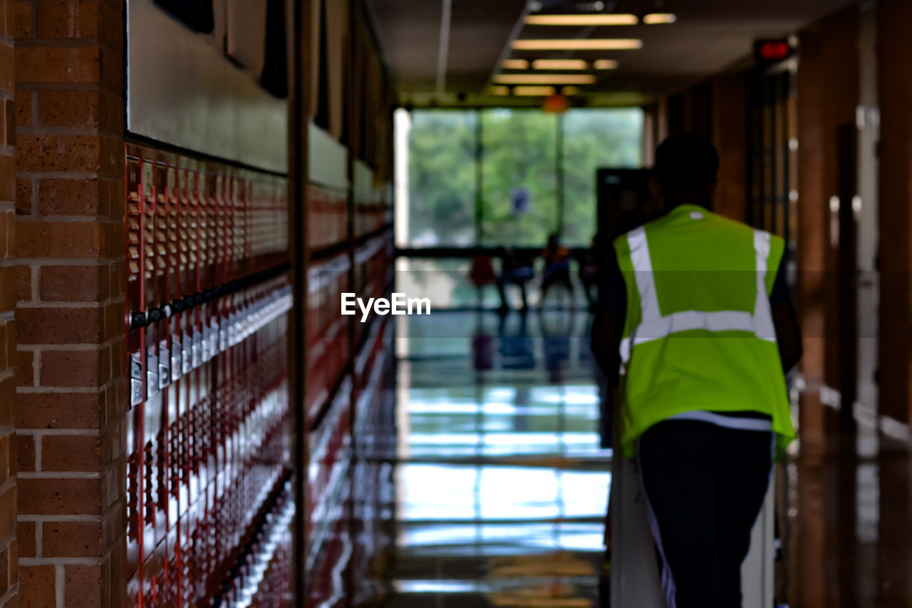 Rear view of man walking in school corridor