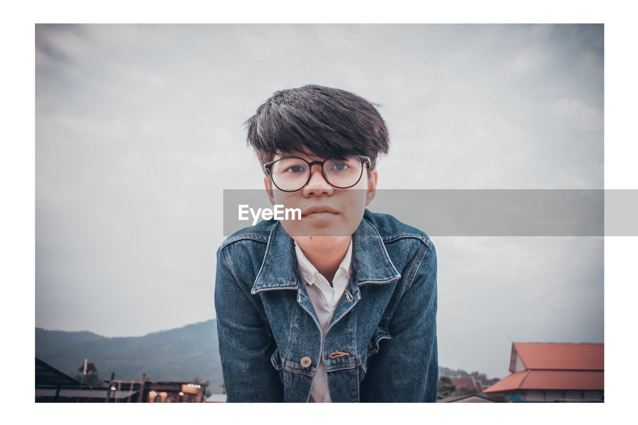 Portrait of boy standing against sky