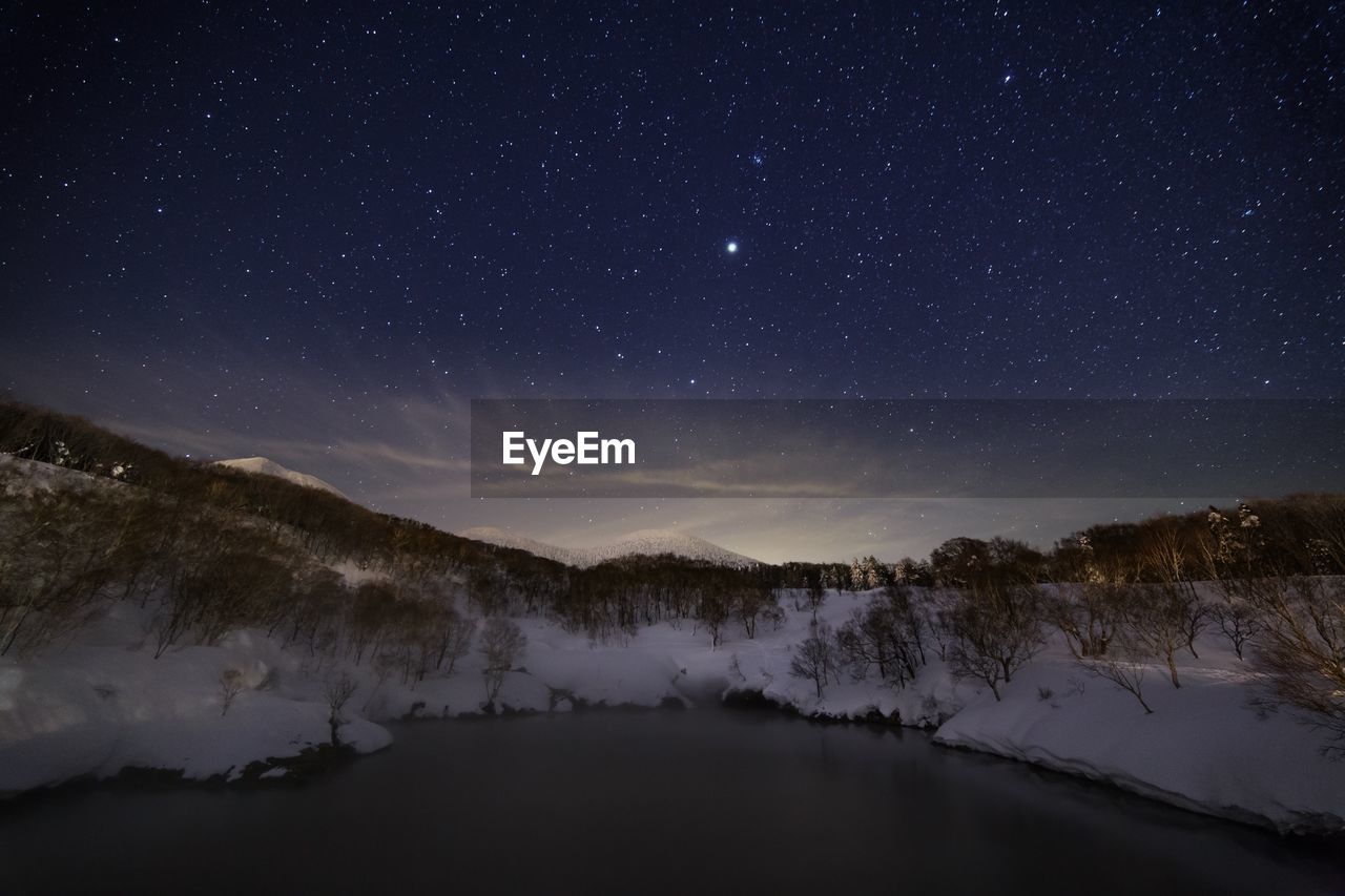 Scenic view of snowcapped mountains and frozen lake against sky at night