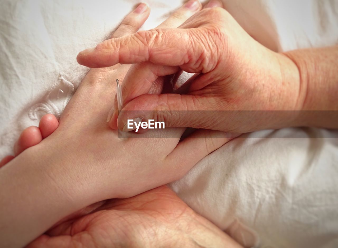 Close-up of woman giving acupuncture to customer on bed