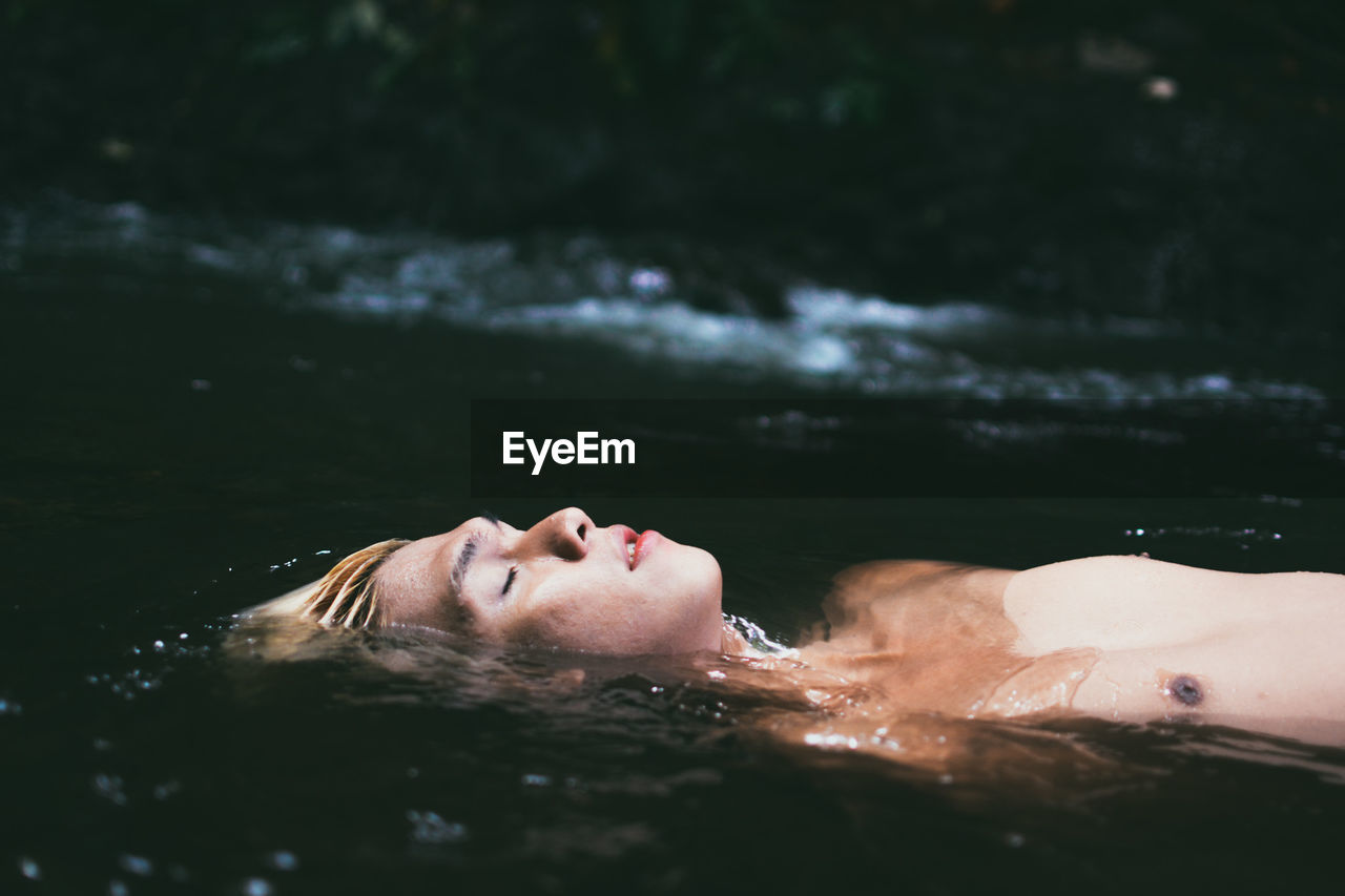 CLOSE-UP OF WOMAN SWIMMING IN LAKE