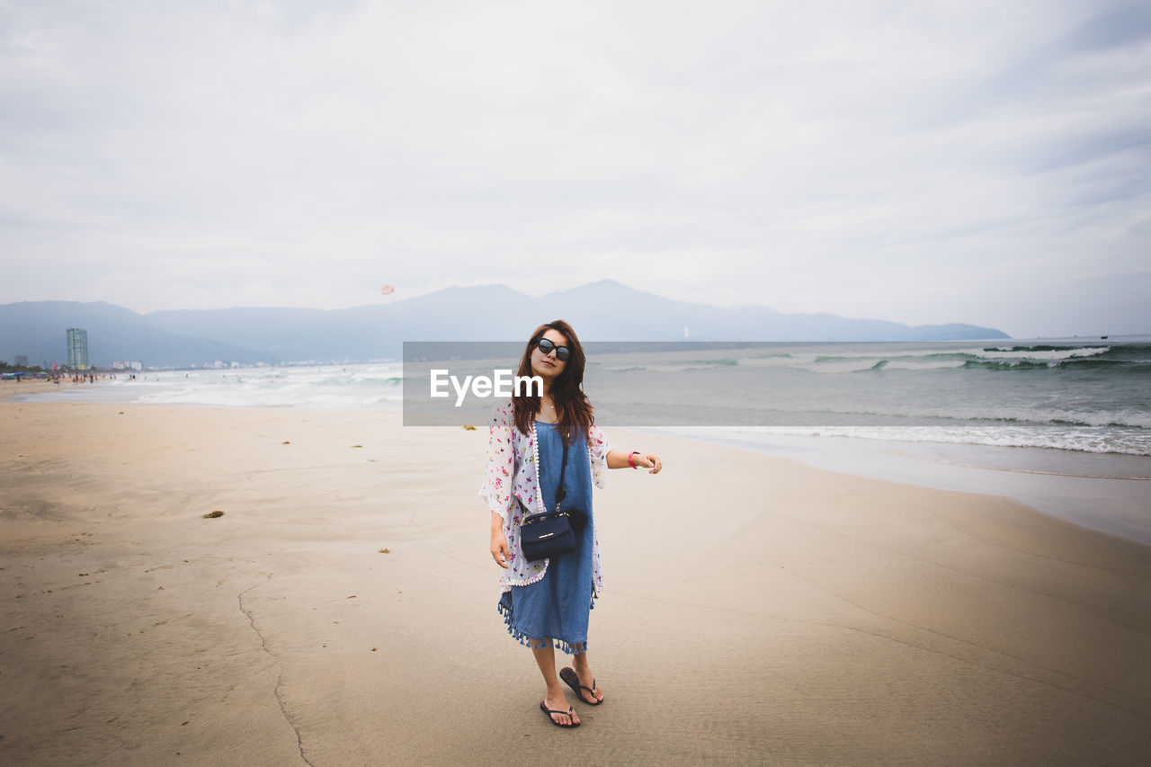 Portrait of woman standing at my khe beach against sky