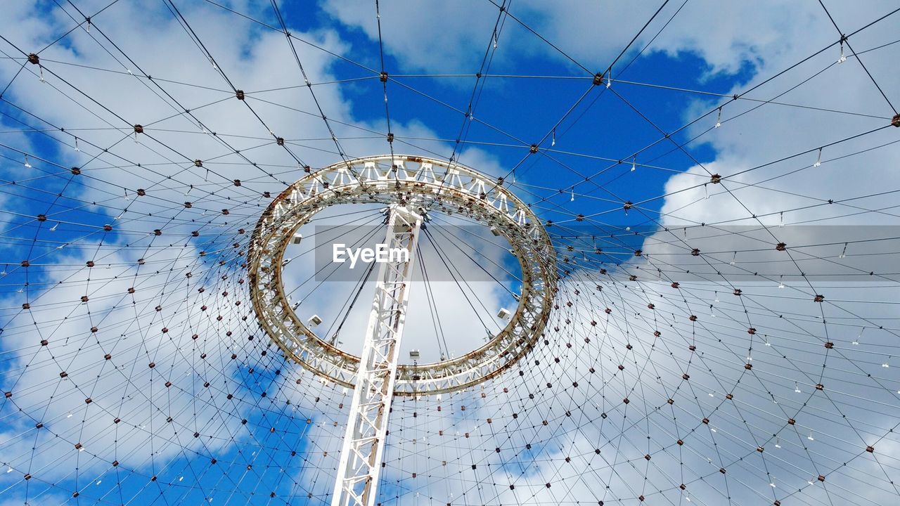 LOW ANGLE VIEW OF FERRIS WHEEL AGAINST BLUE SKY AND CLOUDS