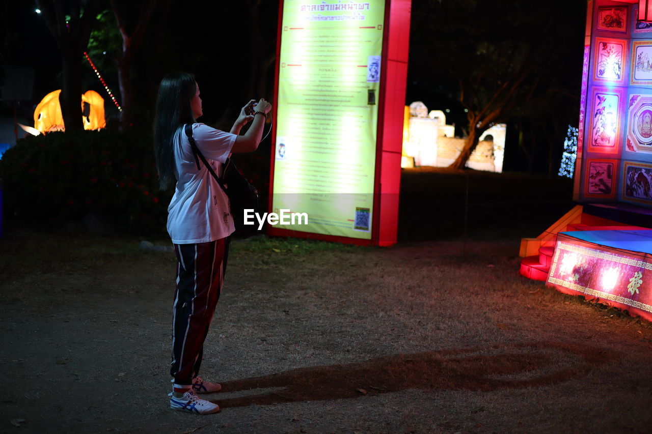 SIDE VIEW OF MAN WITH WOMAN STANDING IN ILLUMINATED STAGE