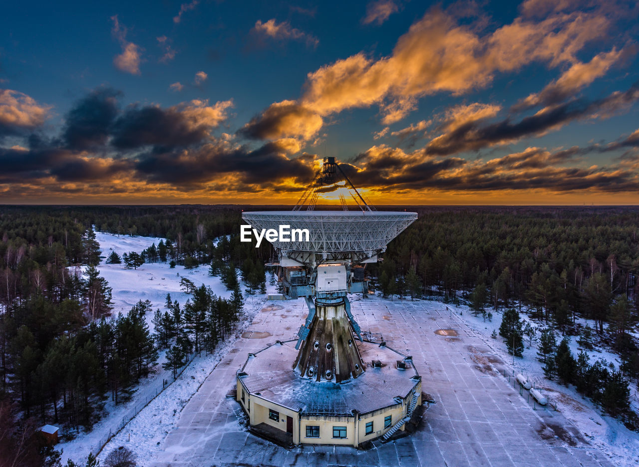 Frozen satellite dish against sky during sunset