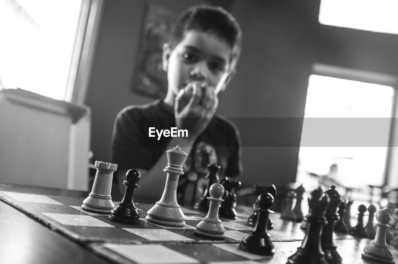 Close-up of chess board against boy eating fruit in background