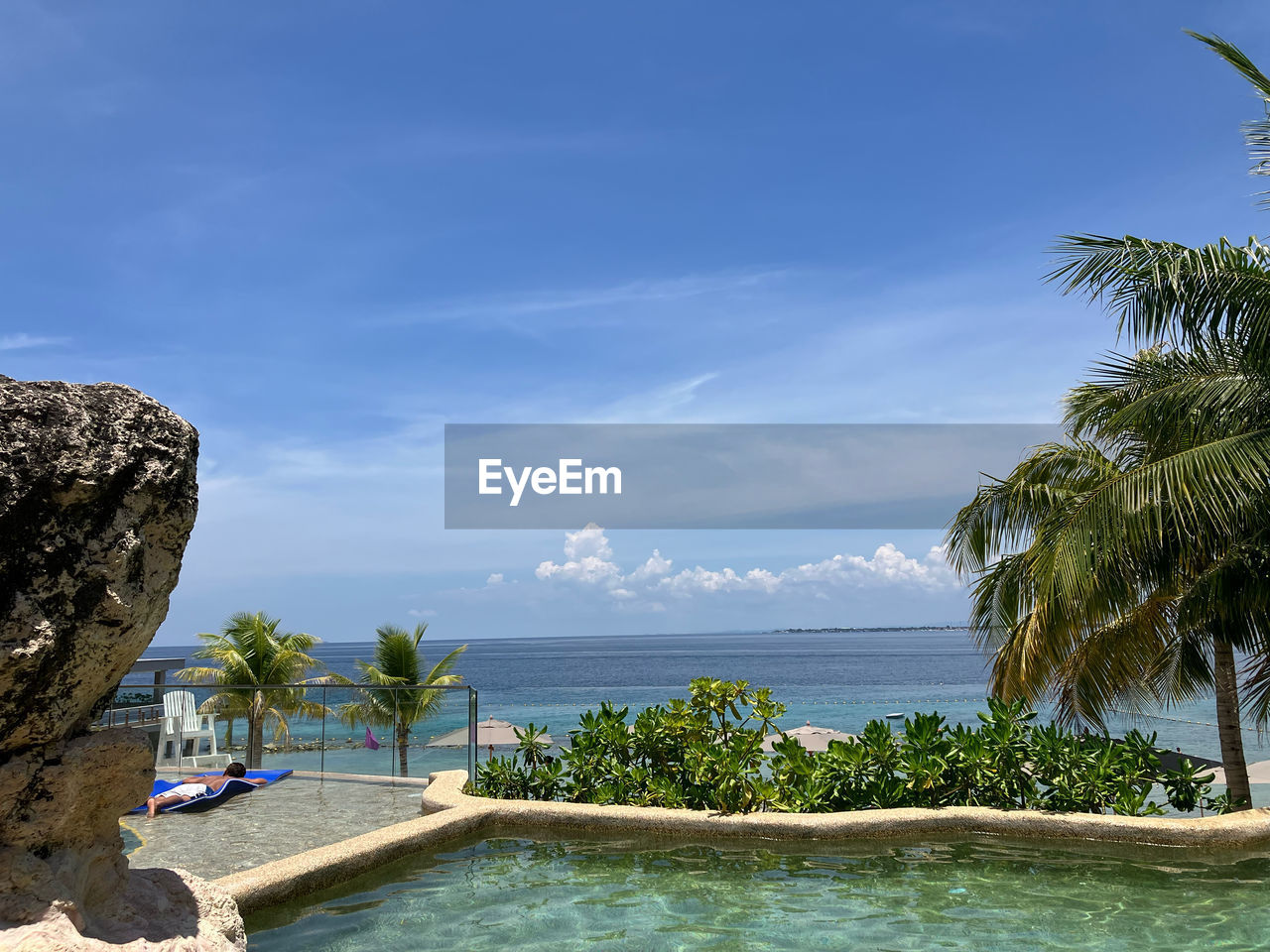 water, vacation, tropical climate, sea, sky, palm tree, nature, tree, land, travel destinations, beach, scenics - nature, beauty in nature, trip, holiday, ocean, plant, tranquility, travel, bay, blue, tranquil scene, tourist resort, coast, cloud, idyllic, swimming pool, relaxation, tourism, day, island, tropics, outdoors, no people, sunlight, environment, luxury, coconut palm tree, wealth, shore, rock, summer, tropical tree, horizon over water, coastline, horizon, resort, architecture, sand, lagoon, hotel, sunny, landscape