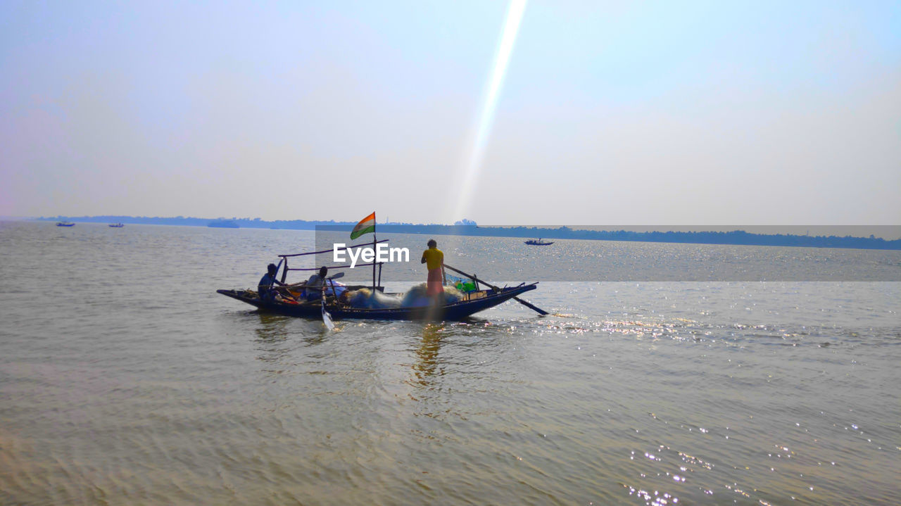 MEN IN BOAT ON SEA AGAINST SKY