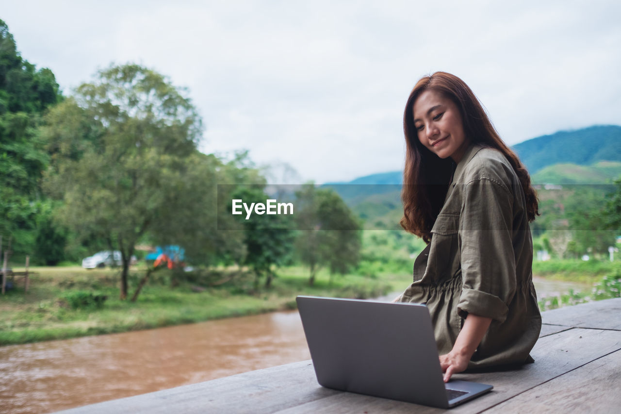 Young woman using laptop while sitting on road