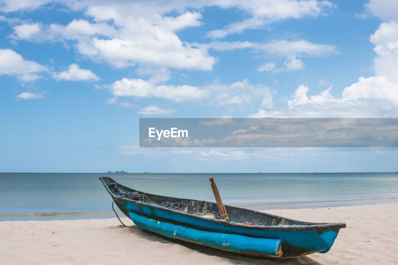 BOAT MOORED ON SEA SHORE AGAINST SKY